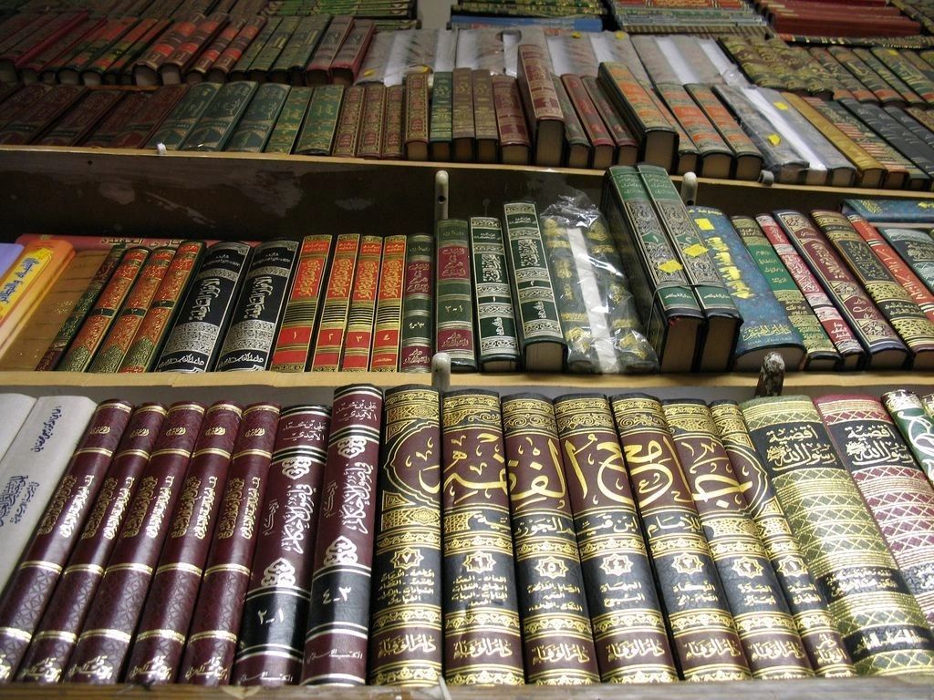 Shelves of Arabic books with gold lettering on their spines.